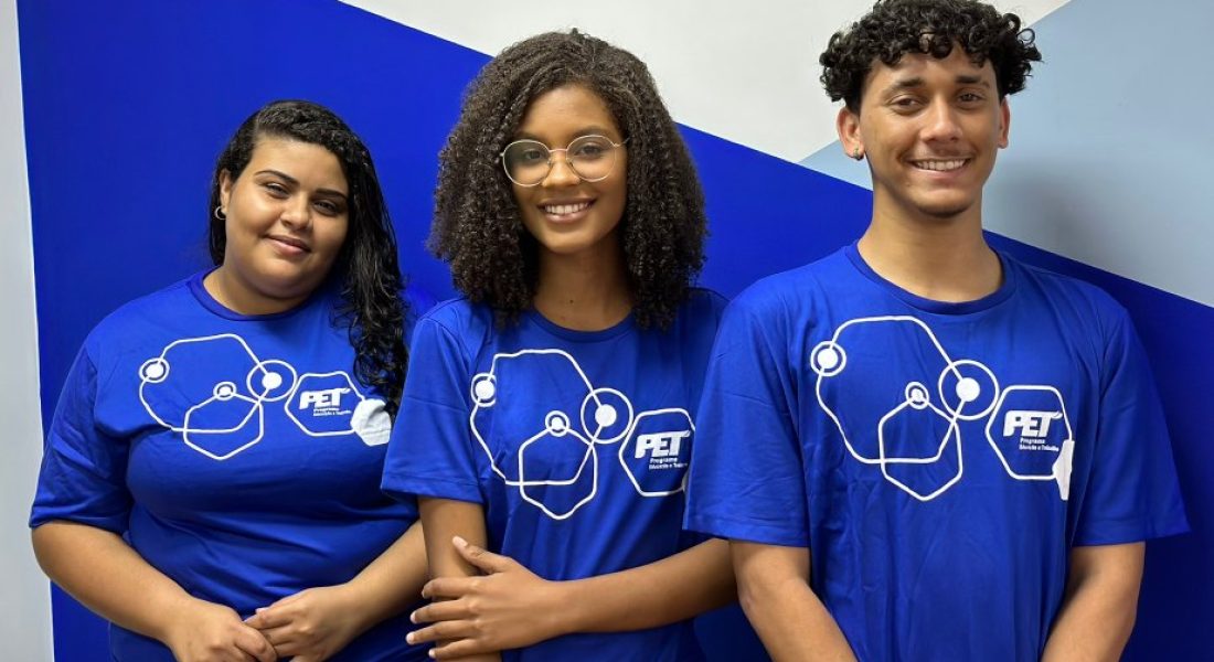 Três adolescentes sorriem com uniformes de Jovem Aprendiz do Programa Educação e Trabalho